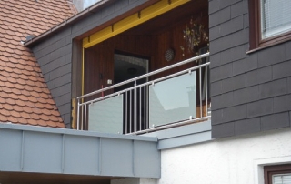 Edelstahlgeländer mit Glasfüllung, Pfosten bestehend aus Edelstahlrohr d=42mm, Ober- und Unterzug d=25mm und senkrechten Stäben d=12mm, aufgesetztem Handlauf d=42mm, VSG aus TVG weiß foliert über Glasklemmhalter befestigt.