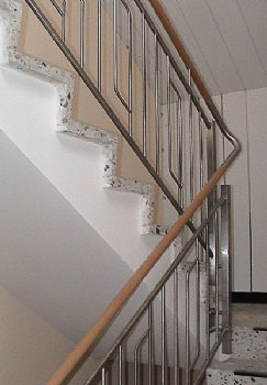 Treppengeländer Pfosten aus Rundrohr d= 42,4 mm, jeweils im Ein- und Austritt abwechselnd an Betonlaibung befestigt. Ober- und Unterzug aus Rohr d= 25 mm mit senkrechten Stäben Rd 12.