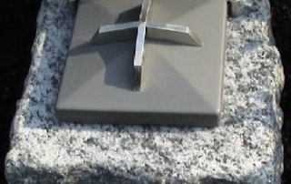 Weihwassergefäß aus Stein mit Stahldeckel und Kreuz.